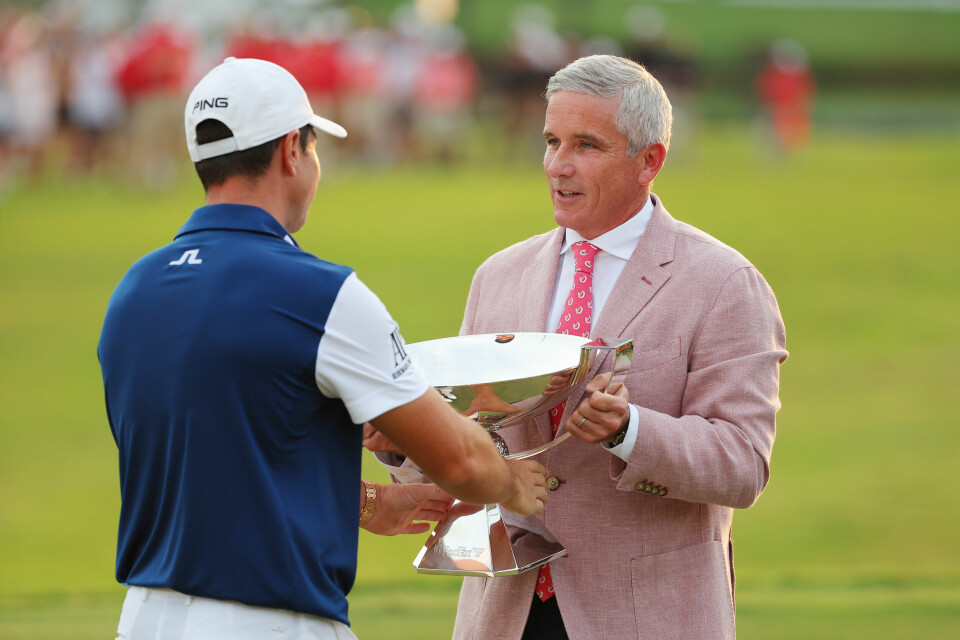 Hovland mottar troféet av PGA-tourens kommisær, Jay Monahan.